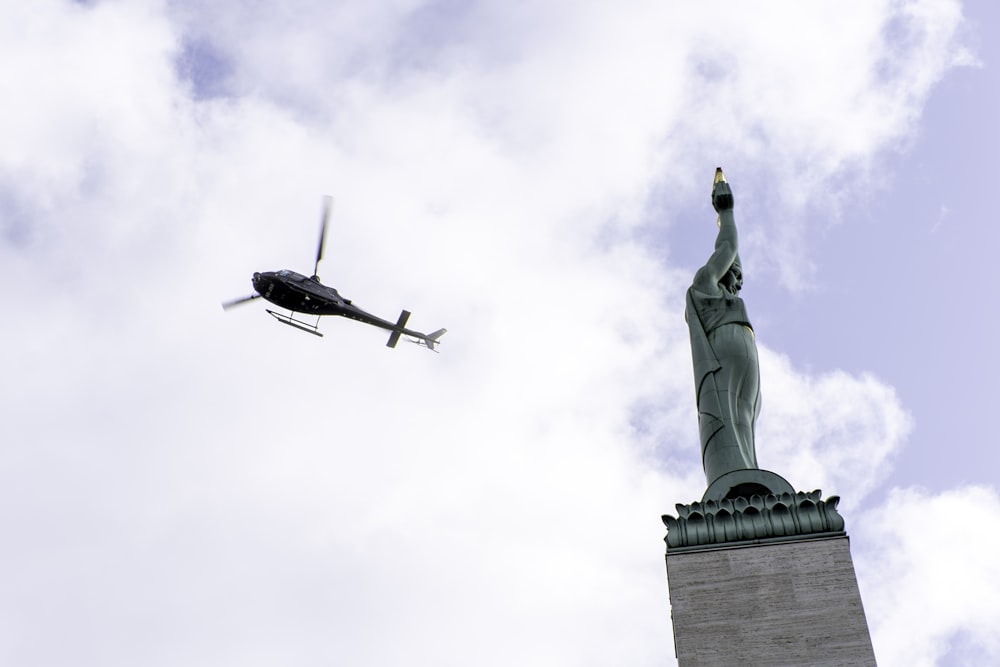 a helicopter flying over the statue of liberty