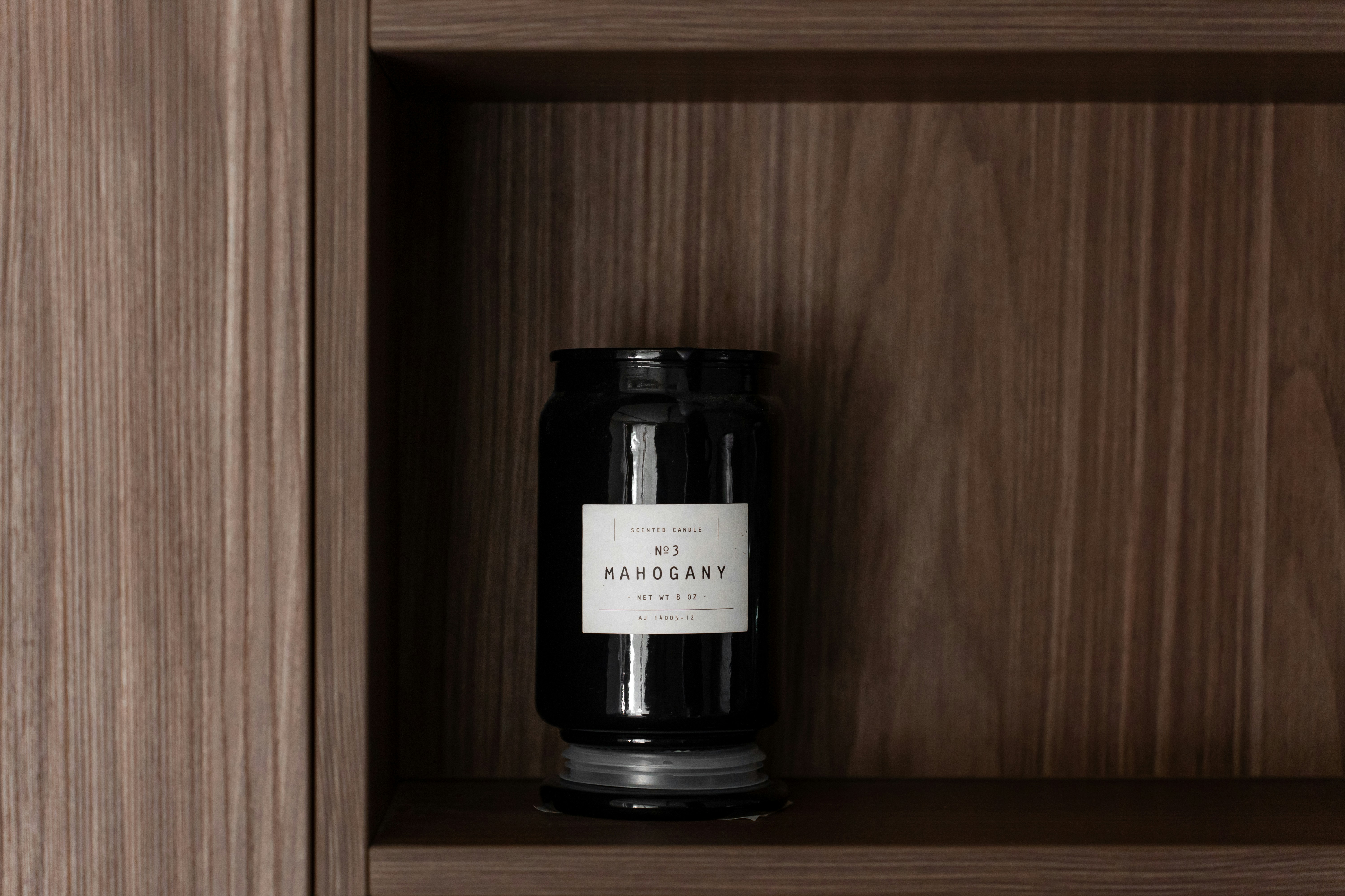 a black candle sitting on top of a wooden shelf
