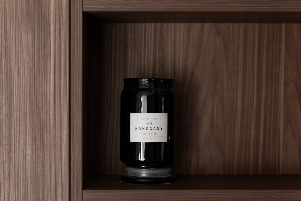 a black candle sitting on top of a wooden shelf