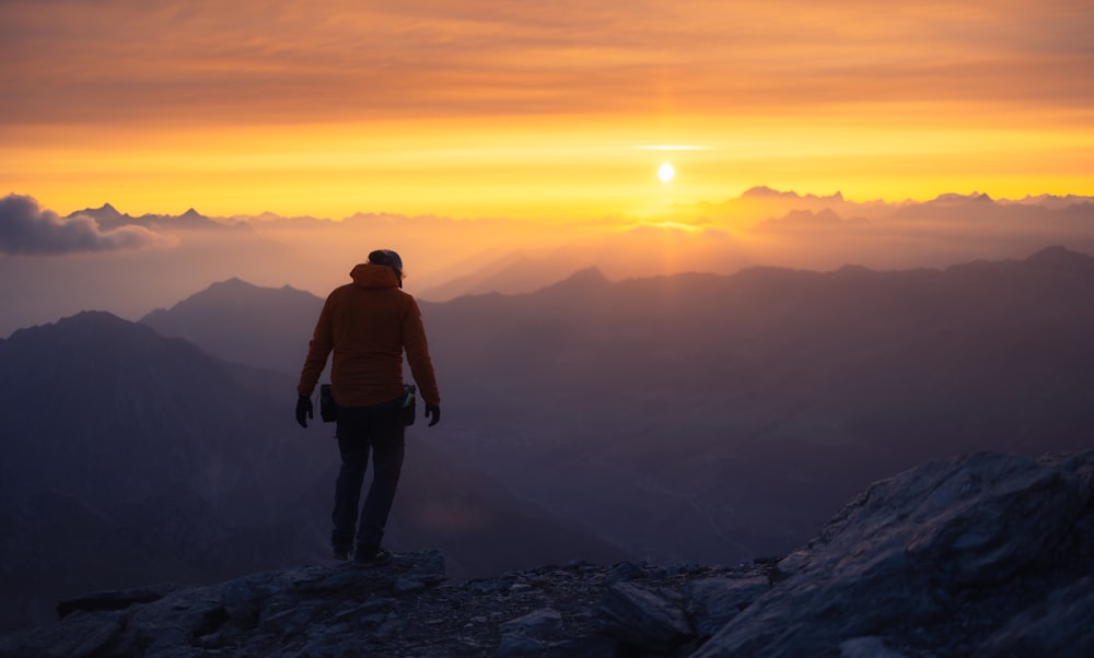 a man standing on top of a mountain at sunset