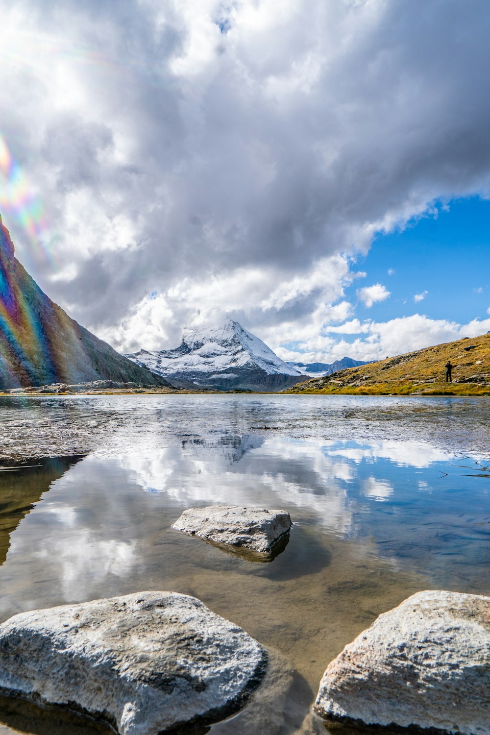 a lake with rocks and a mountain in the background