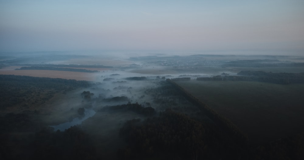 an aerial view of a foggy landscape at dusk