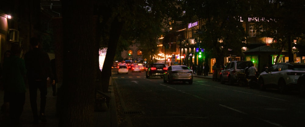 a city street at night with cars parked on the side of the road