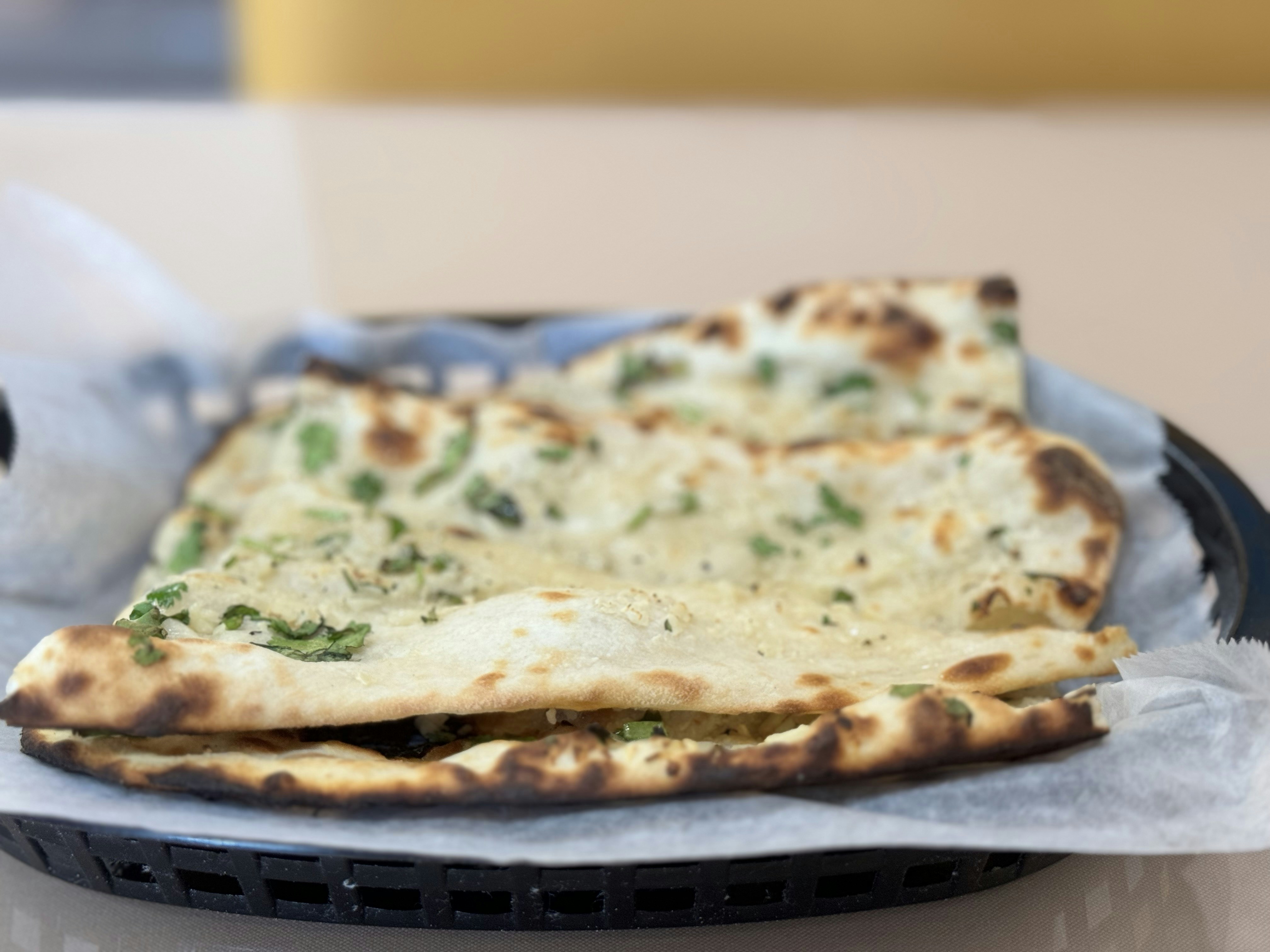 Freshly baked naan bread with garlic and herbs coming out of a clay tandoor oven