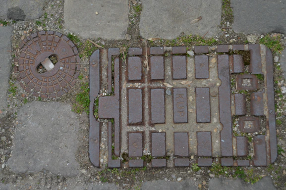 Close-up of a sturdy, industrial manhole cover resting on a cobblestone street.