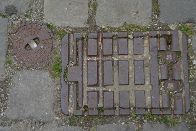 Workers installing sturdy FRP manhole covers on an urban street under bright sunlight.