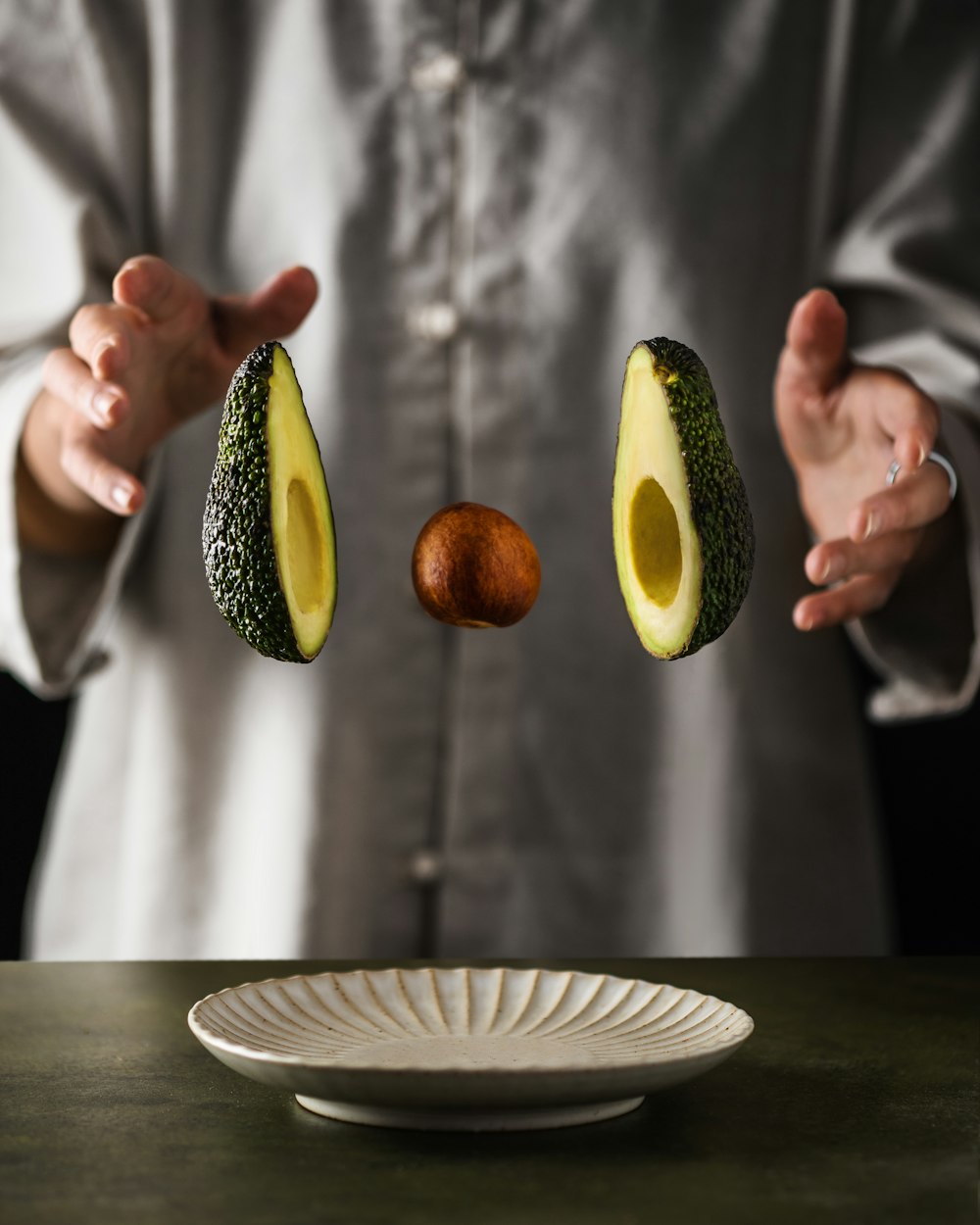 an avocado being cut in half by a person