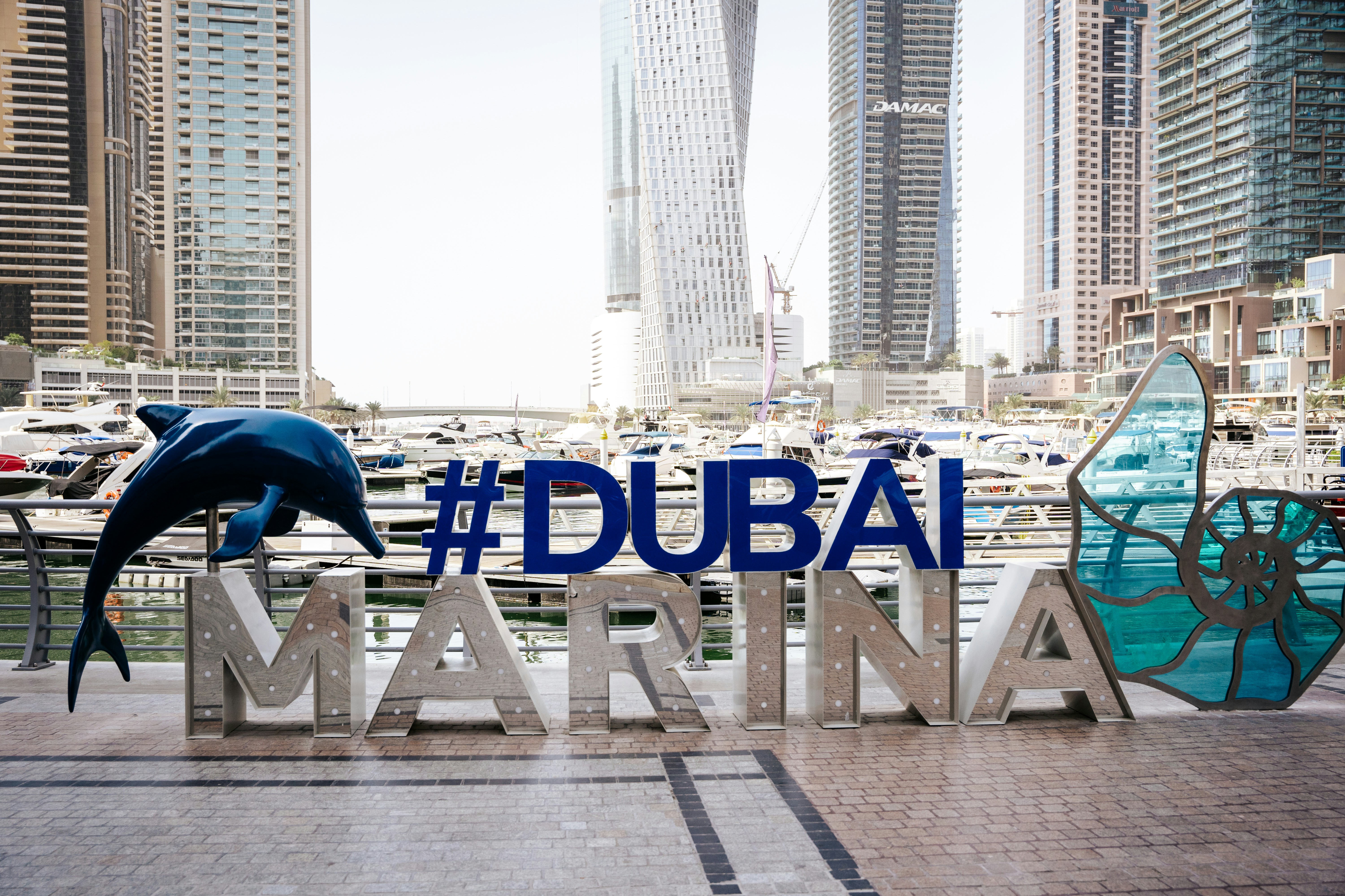 a sign that says dubai marina with a dolphin statue in front of it