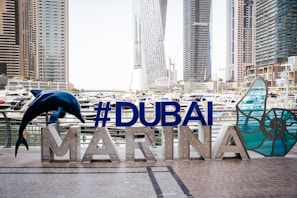 a sign that says dubai marina with a dolphin statue in front of it