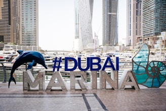 a sign that says dubai marina with a dolphin statue in front of it
