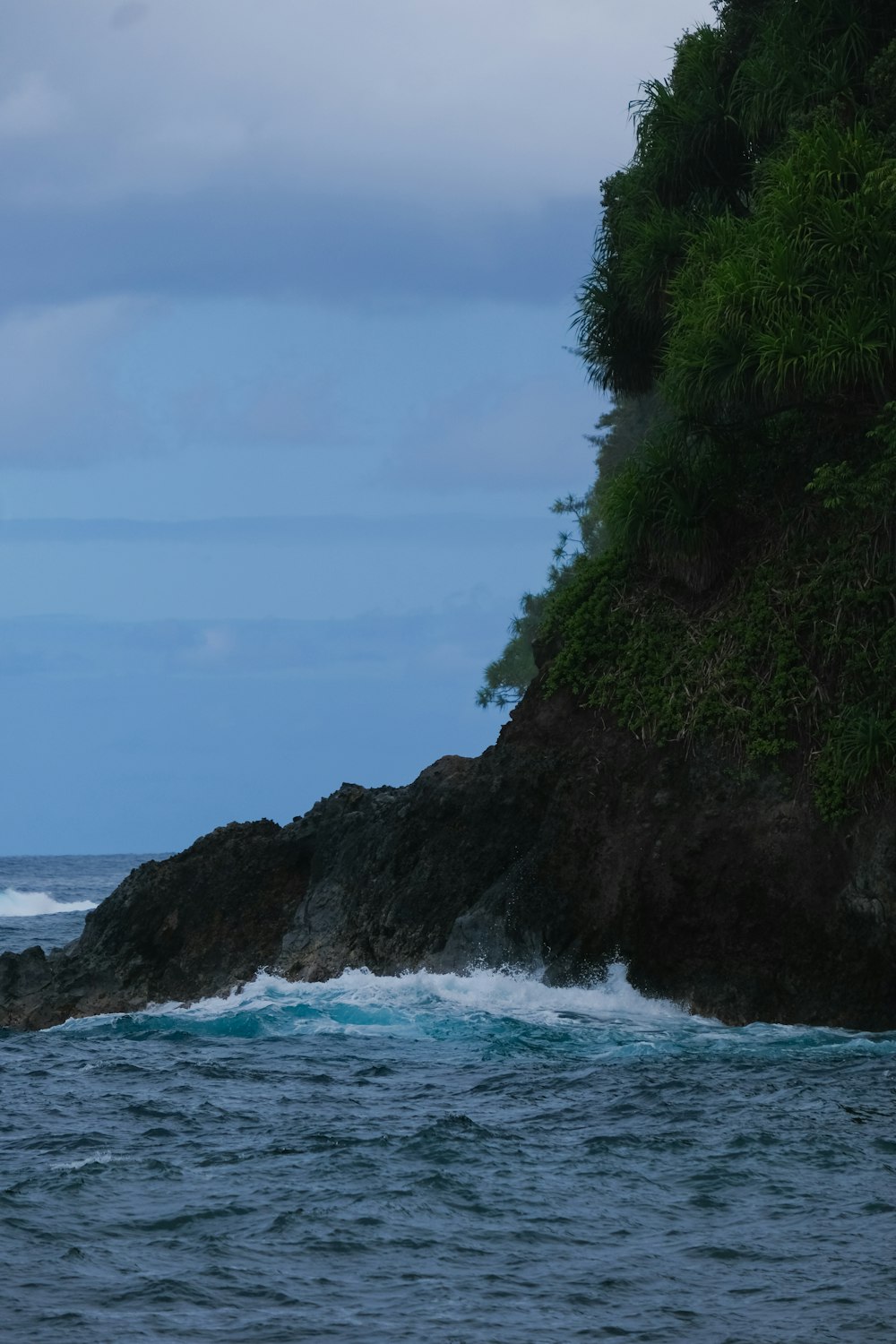 a large body of water next to a lush green hillside