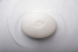 A whimsical soap shaped like a smiling face resting on a soft pastel surface.