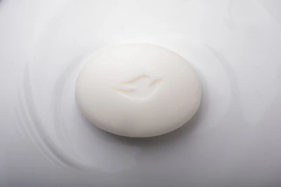 A whimsical soap shaped like a smiling face resting on a soft pastel surface.