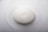 A smooth, oval-shaped white soap bar embossed with a simple bird design rests on a glossy white surface.