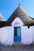 a white building with a blue door and a black roof
