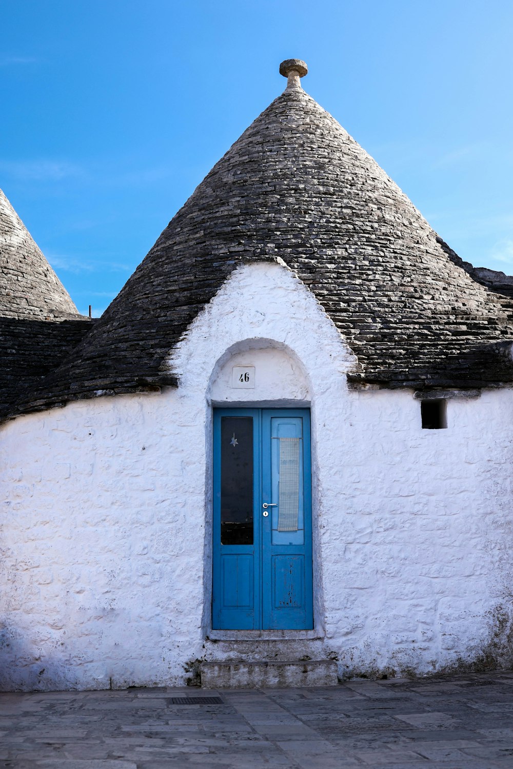 a white building with a blue door and a black roof