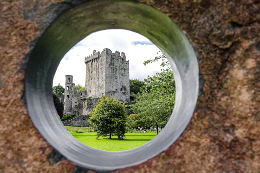 a view of a castle through a hole in a rock wall