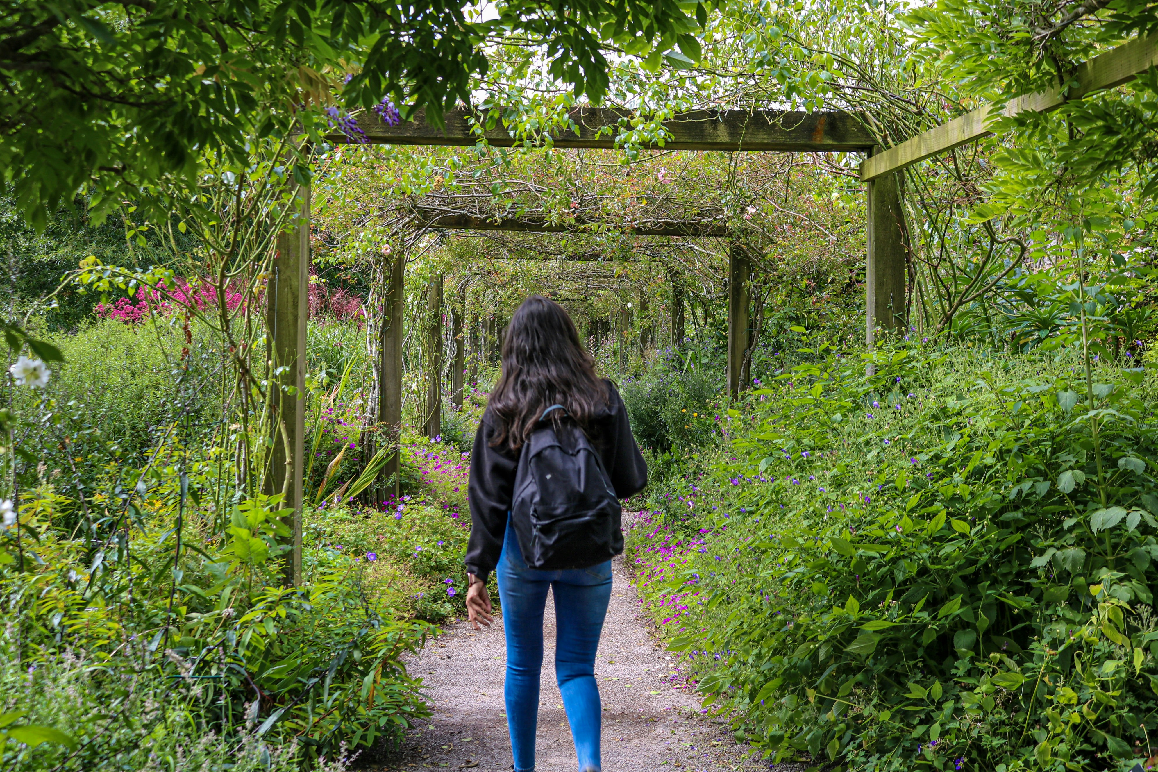 uma mulher caminhando por um caminho em um jardim