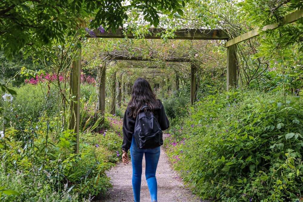 a woman walking down a path in a garden