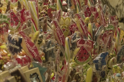 An assortment of colorful sweets, including lollipops and candies, are wrapped in clear packaging with the word 'Barcelona' written on some of them. The candies display a variety of shapes, including animals, fruit, and traditional lollipop swirls.