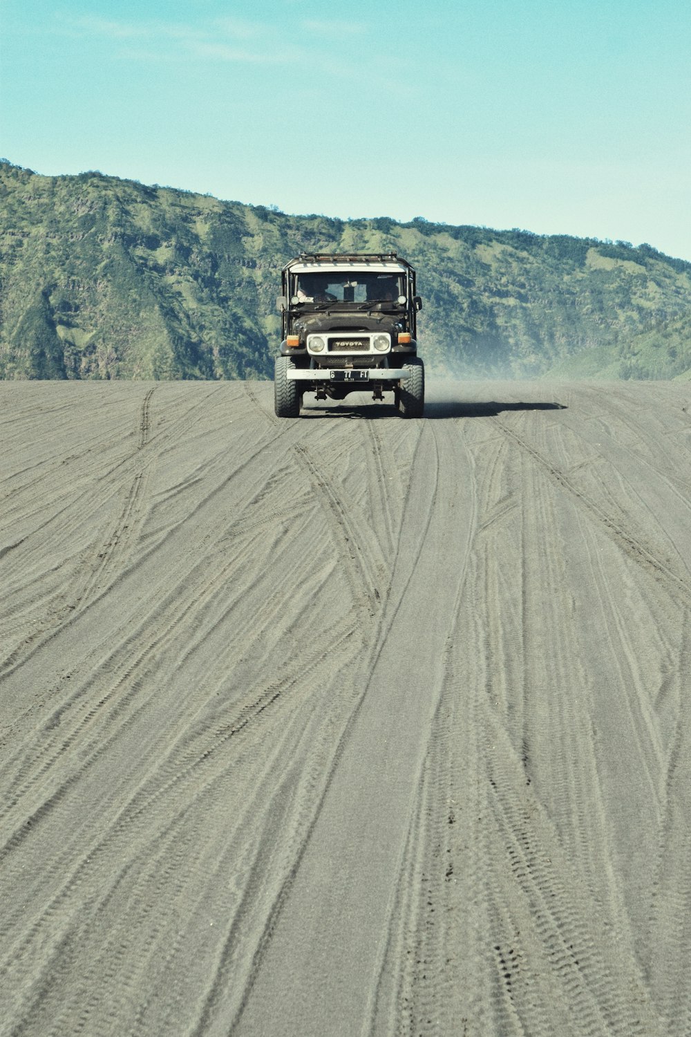 a truck driving down a dirt road near a mountain