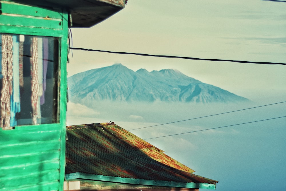 a green building with a mountain in the background