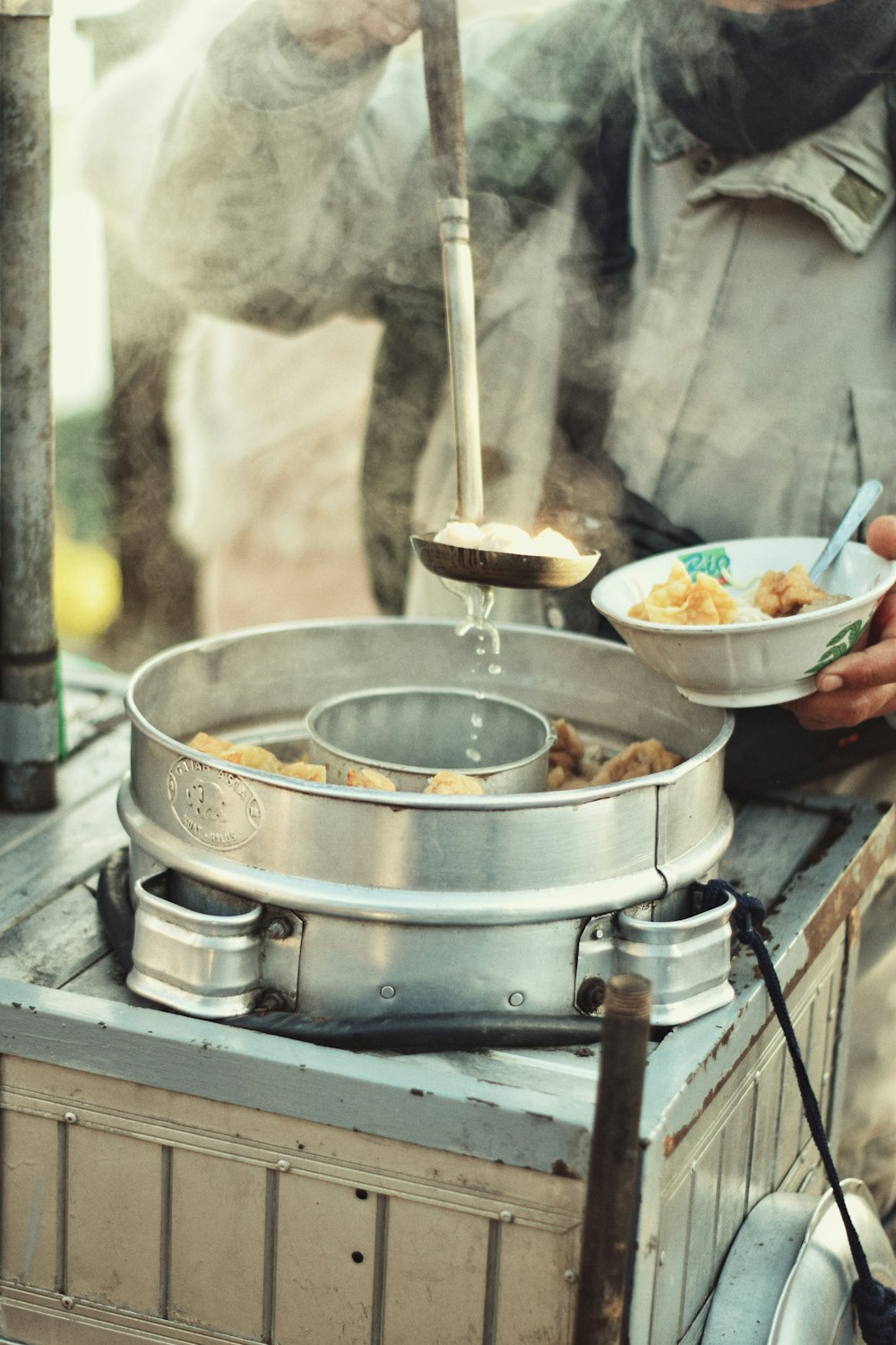 a man standing over a bowl of food on top of a stove