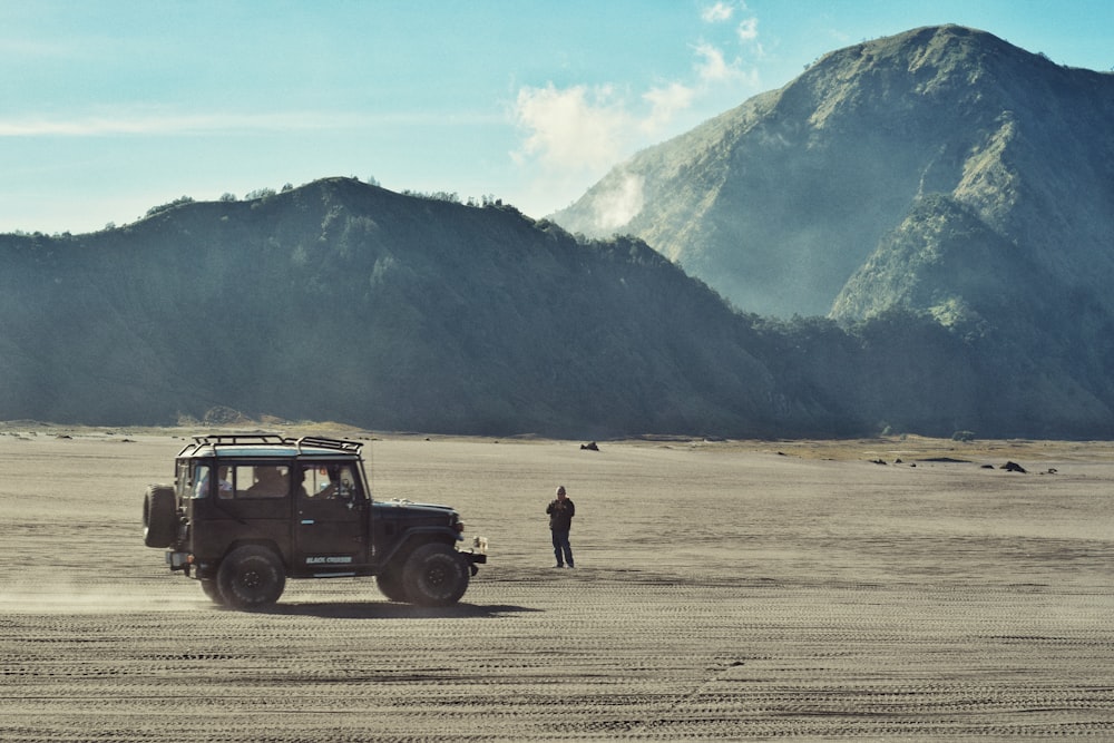 a man standing next to a jeep in the desert