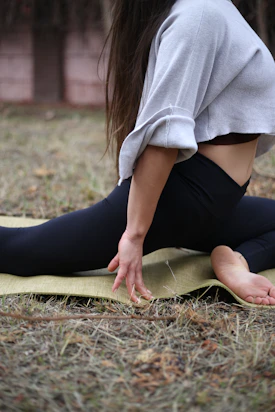 a woman sitting on a yoga mat in a park