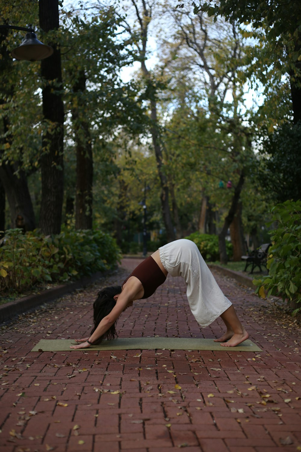 a woman is doing a yoga pose on a brick path