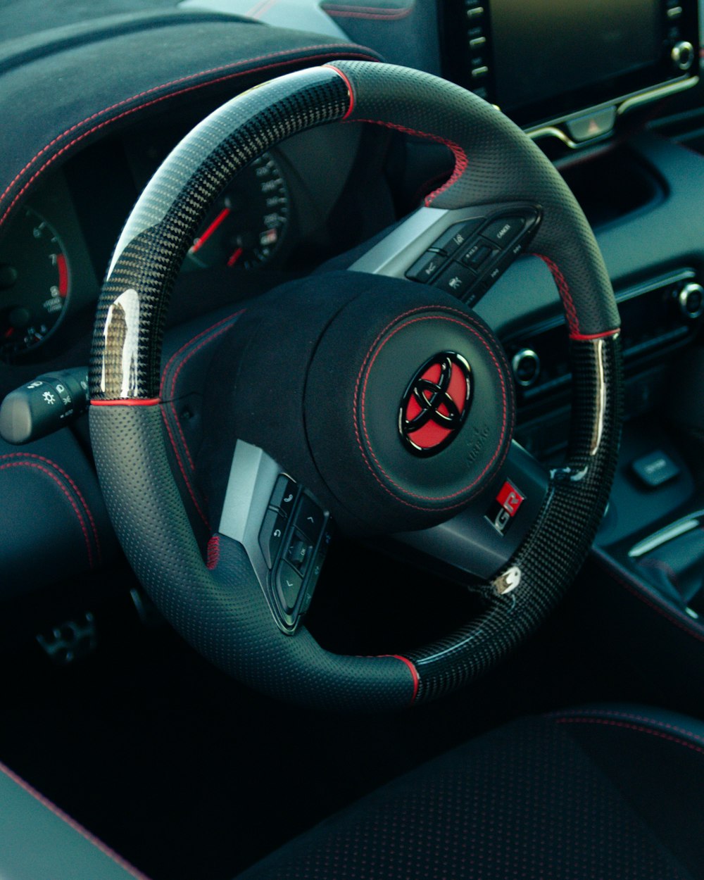 a steering wheel of a car with a red stitch