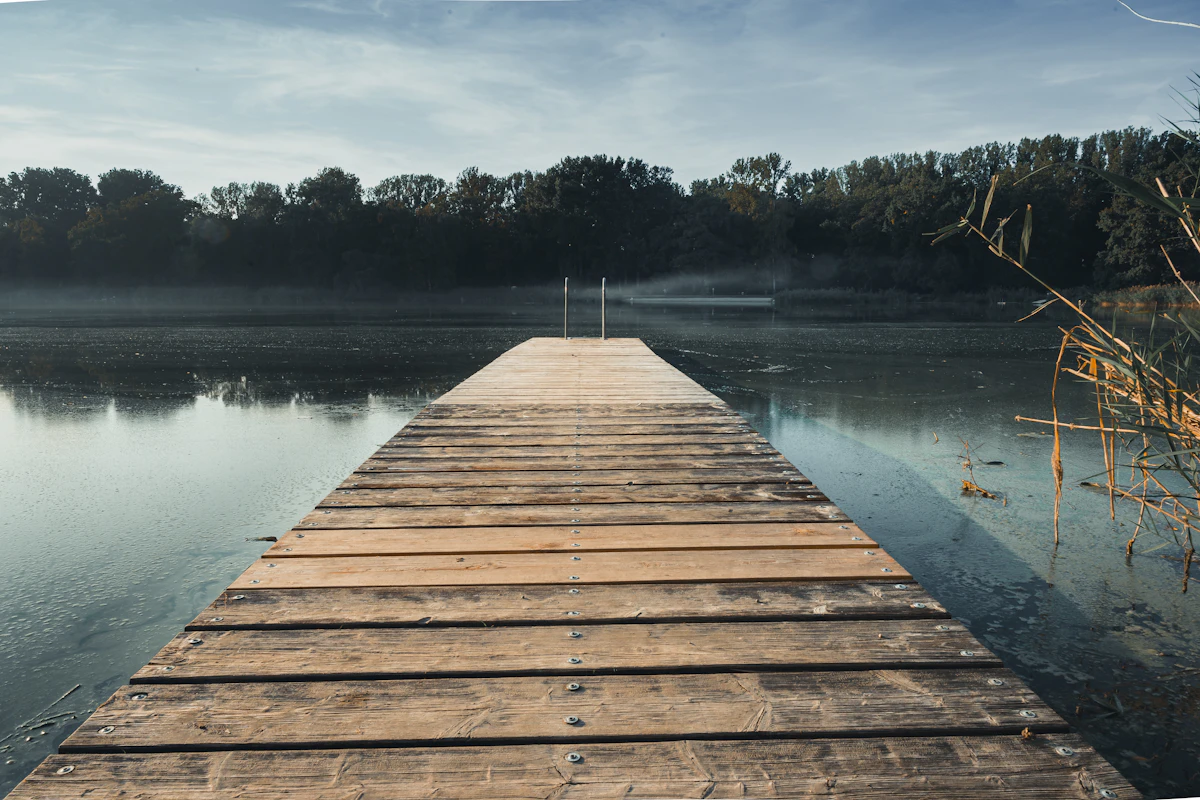 A wooden dock reaching into a calm, forest-lined lake