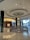 A luxurious indoor shopping mall featuring high-end stores such as Louis Vuitton. The mall has glossy tiled floors, a large central chandelier descending from the ceiling, and plenty of ambient lighting. The decor is modern and sophisticated, with clean lines and a spacious layout.