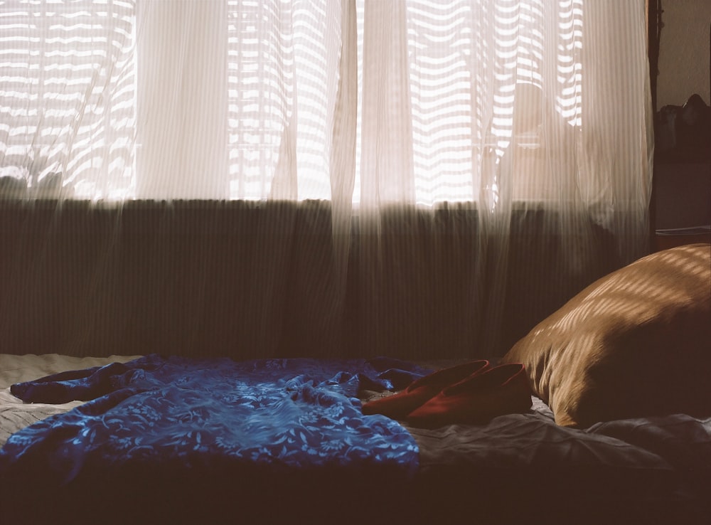 a bed in front of a window with a blue blanket on it