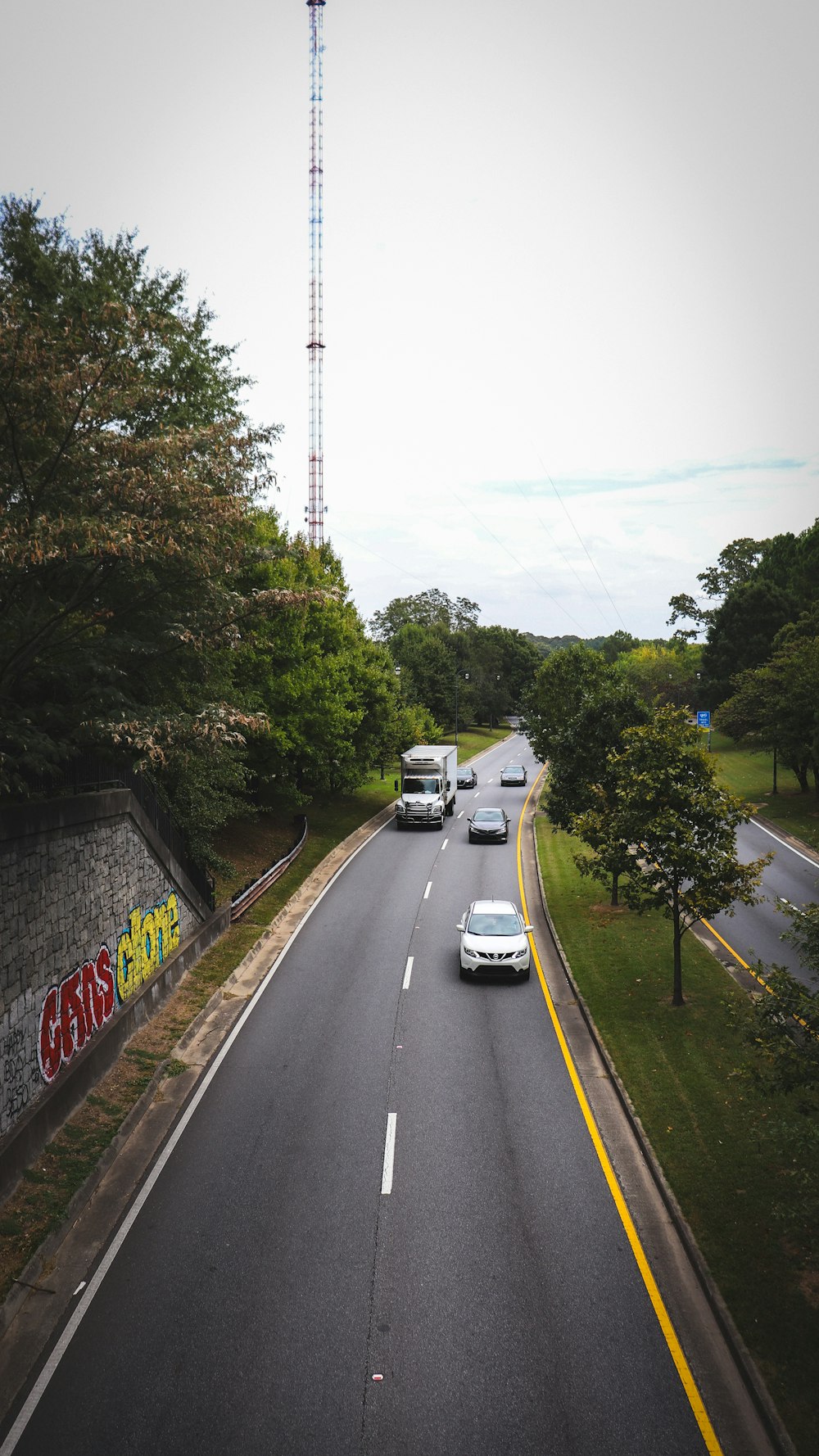 a street with cars driving down it and a radio tower in the background