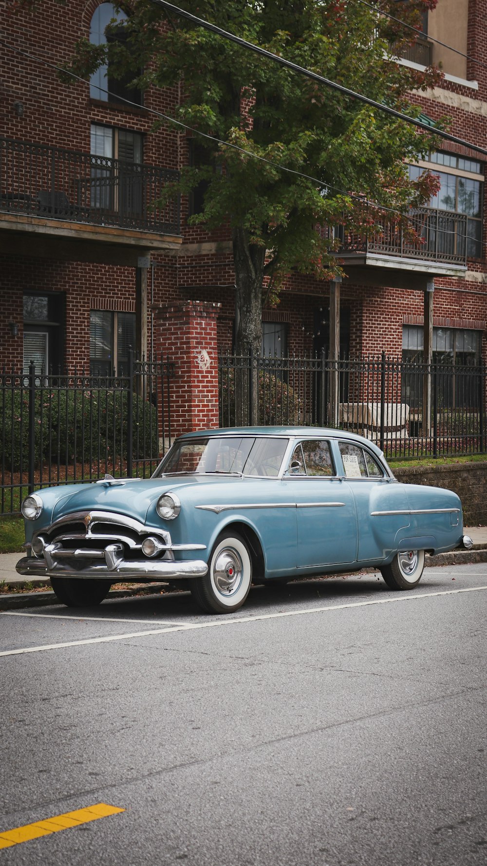 an old blue car parked on the side of the road