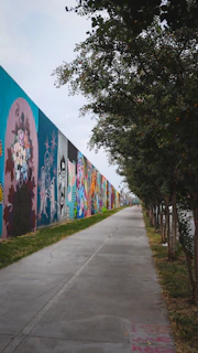 Community artists painting a mural with traditional Mexican motifs and vibrant colors along a canal pathway.