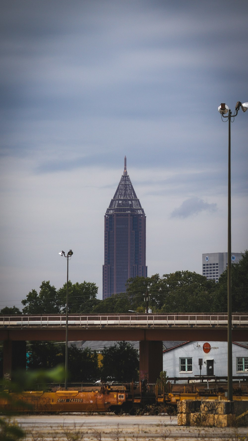 a train traveling past a tall building under a cloudy sky