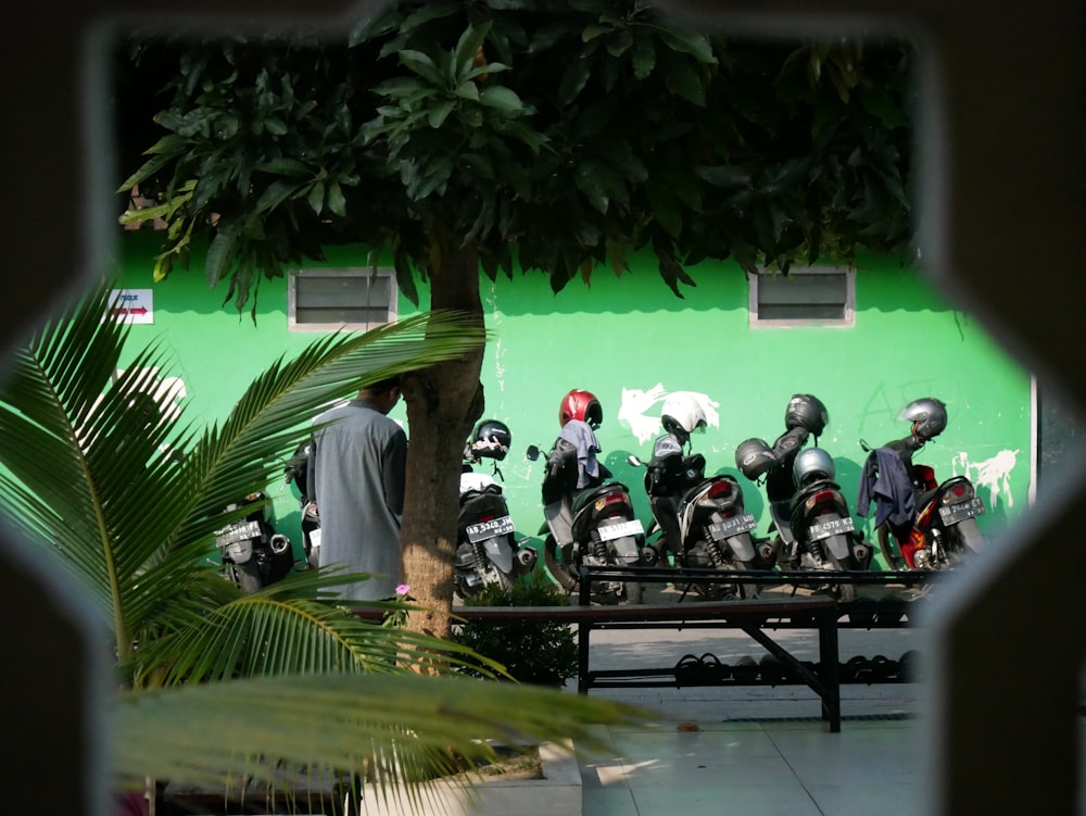 um grupo de motocicletas estacionado ao lado de um muro verde
