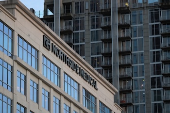 A modern building with the sign 'Northside Medical' prominently displayed. The structure features large glass windows reflecting the light. In the background, there is a high-rise apartment building with numerous balconies and windows, showcasing an urban setting.