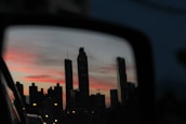 City skyline viewed from the tinted window of a luxury vehicle cruising through at dusk.