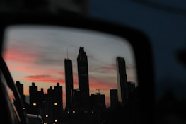 City skyline viewed from the tinted window of a luxury vehicle cruising through at dusk.