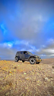 A rugged black SUV ready for adventure, showcased on the lot with a clear blue sky.