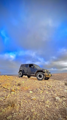 A rugged SUV standing on a dirt trail beneath a vibrant blue sky.