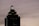 A tall, dark skyscraper is silhouetted against a cloudy sky. The building has a prominent logo with the letters 'HH' illuminated near the top. The outline of the structure is highlighted by lights on each tier, and there is a sign that reads 'Truist' along one side.