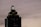 A tall, dark skyscraper is silhouetted against a cloudy sky. The building has a prominent logo with the letters 'HH' illuminated near the top. The outline of the structure is highlighted by lights on each tier, and there is a sign that reads 'Truist' along one side.