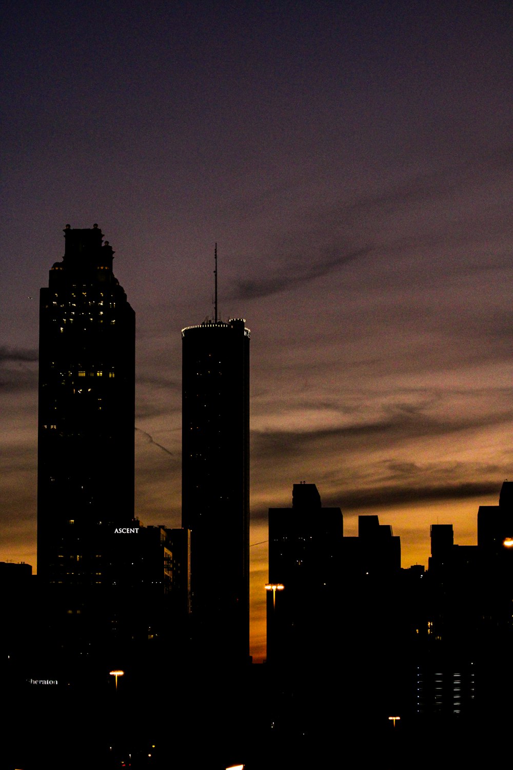 a city skyline at night with a plane flying in the sky