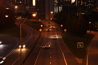 A tow truck with flashing lights pulling a car on a highway at dusk.