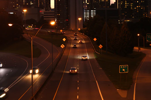 A tow truck with flashing lights pulling a car on a highway at dusk.