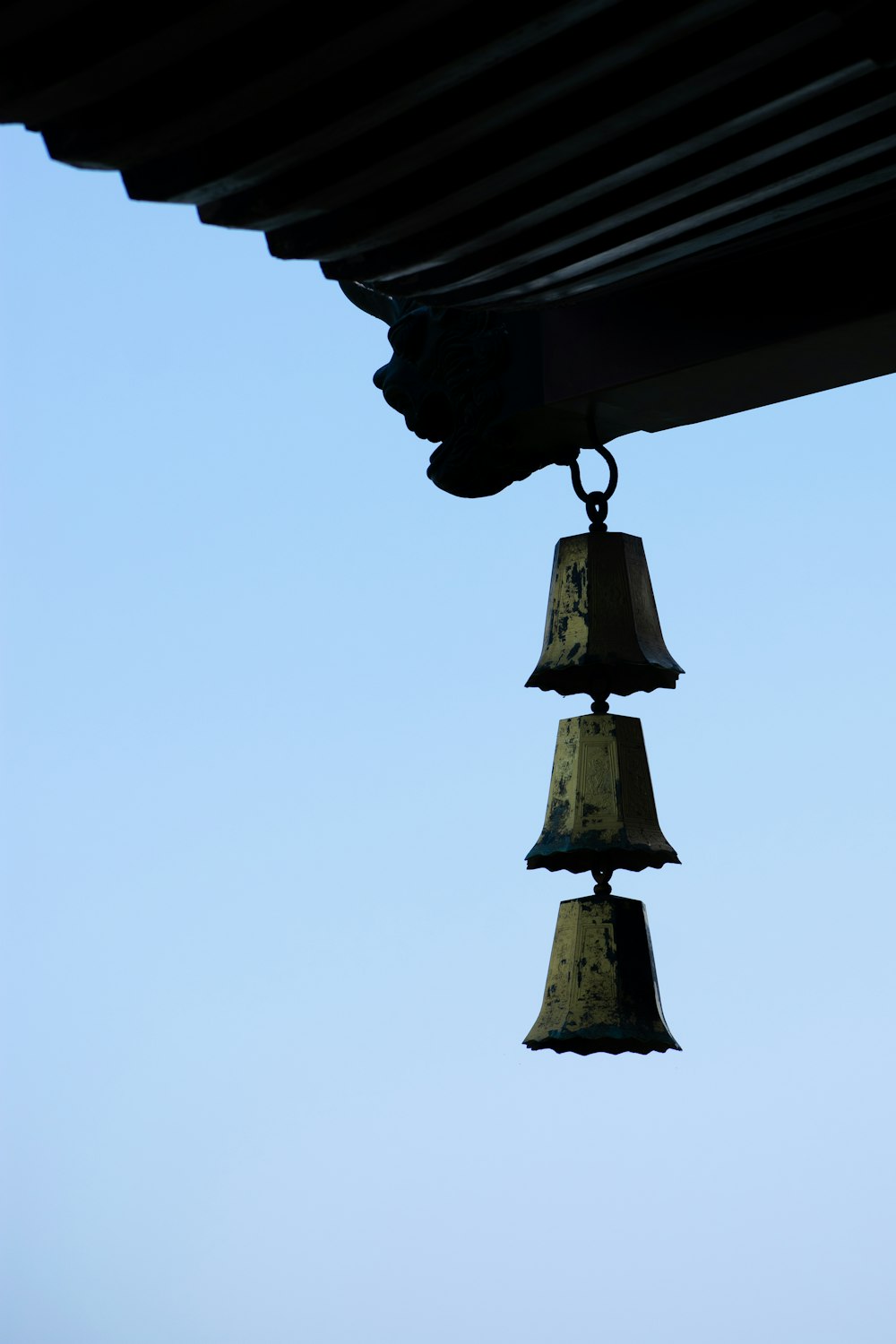 three bells hanging from the roof of a building